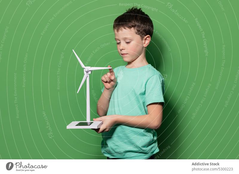 Lächelndes Kind mit Windrad-Mockup Junge Kraft Attrappe Windmühle Energie eolicisch Erzeuger Fokus lässig regenerativ alternativ Energetik Kindheit positiv