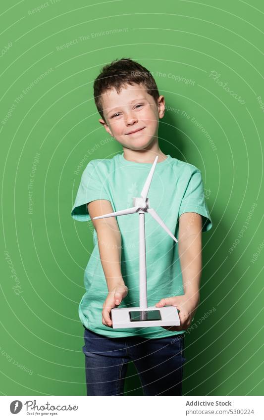 Lächelndes Kind mit Windrad-Mockup Junge Glück Kraft Attrappe Windmühle Energie eolicisch Erzeuger Fokus lässig heiter froh Freude Kindheit positiv aufgeregt