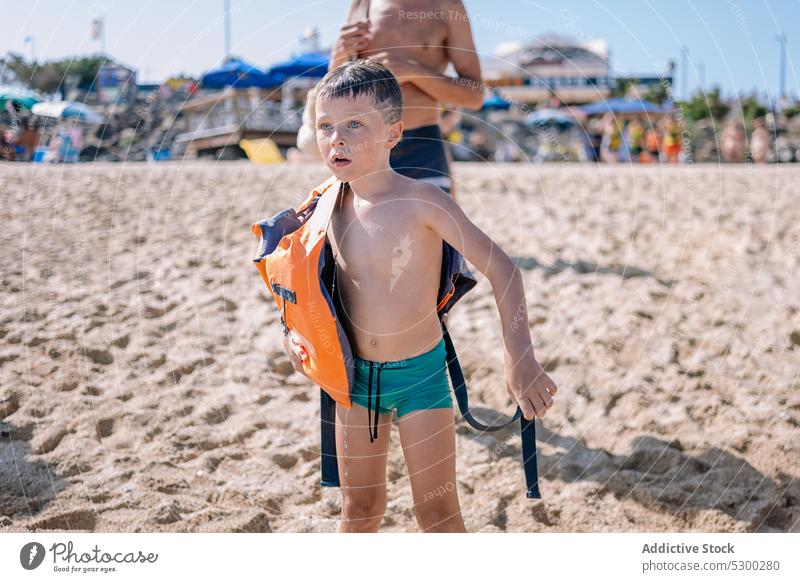 Kleiner Junge steht am Sandstrand Strand Sommer Mann Kind Ufer Sommerzeit Küste Vater beobachten Kindheit wenig Sonne Feiertag Küstenlinie Erholung nachdenken