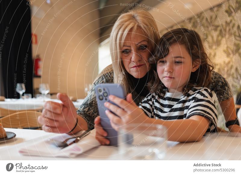Frau und Mädchen machen Selfie mit Smartphone Großmutter Enkelin Restaurant Zusammensein Gedächtnis Apparatur fotografieren Mobile Café ernst Gerät Tisch