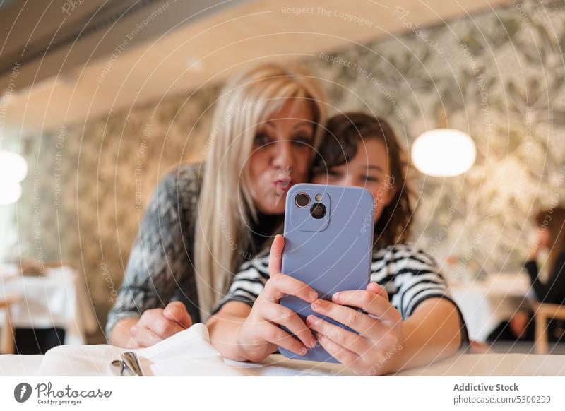 Positive Frau und Mädchen nehmen Selfie auf Smartphone Großmutter Enkelin Restaurant Zusammensein Glück Lächeln heiter Gedächtnis Apparatur fotografieren Mobile