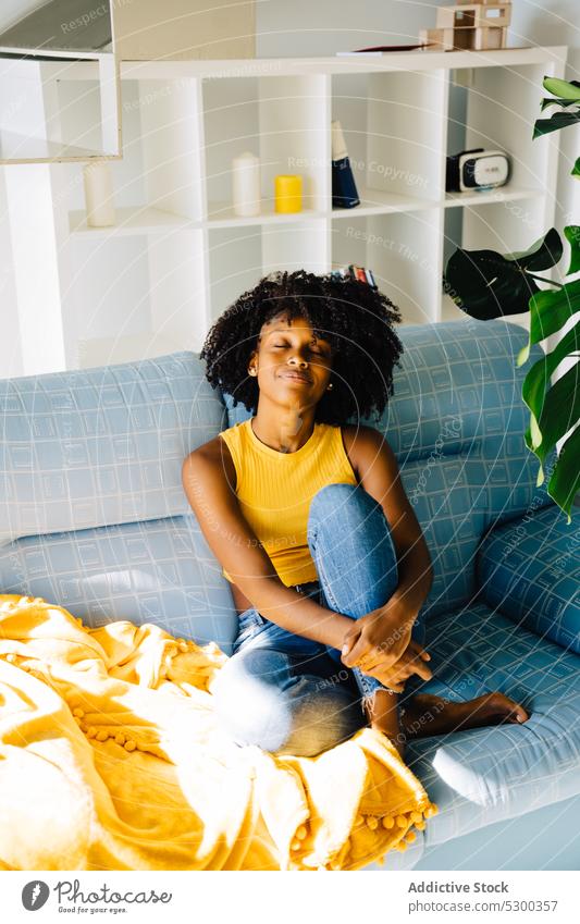 Ruhige schwarze Frau auf Sofa liegend ruhen Inhalt sich[Akk] entspannen genießen heimwärts Lächeln Augen geschlossen Komfort Afro-Look Liege