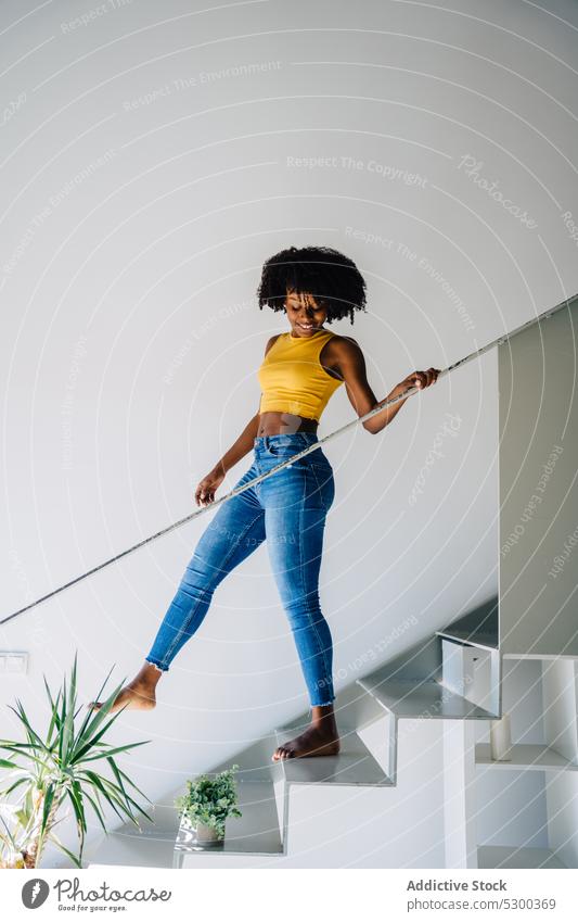 Positive schwarze Frau geht die Treppe hinunter Afro-Look Schritt Lächeln Glück Reling heiter heimwärts krause Haare trendy Outfit lässig modern jung