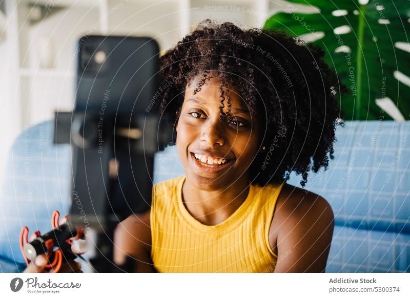 Glückliche schwarze Frau mit Mikrofon im Wohnzimmer vlog Videoanruf Smartphone Blogger Lächeln benutzend online Kommunizieren Video-Chat heiter Afroamerikaner