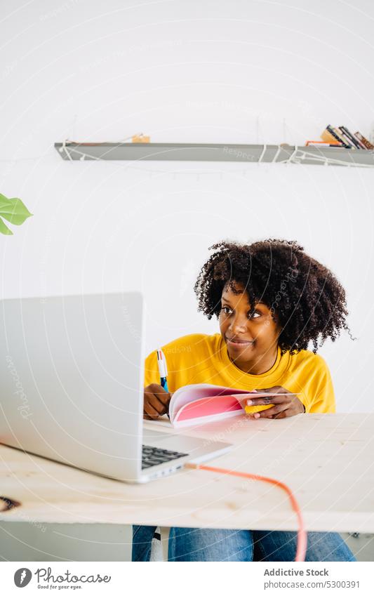 Fokussierte schwarze Frau, die Informationen in ein Notizbuch schreibt Laptop zur Kenntnis nehmen schreiben Schüler lernen Bildung Konzentration jung
