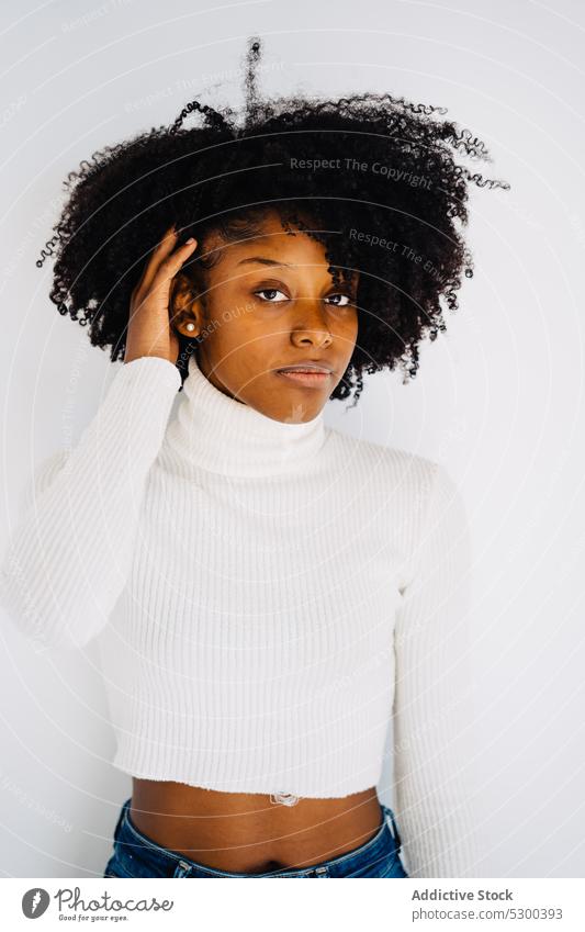 Schlanke schwarze Frau in weißem Studio Haare berühren Model Stil Vorschein Porträt Frisur lässig Afro-Look trendy Afroamerikaner Bekleidung krause Haare jung