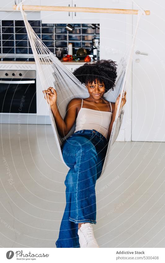 Zufriedene schwarze Frau auf Hängematte ruhend heimwärts hängen Küche Lächeln sich[Akk] entspannen Afro-Look Komfort Glück Afroamerikaner jung lässig positiv