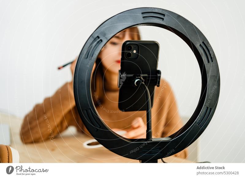 Beauty-Vlogger macht Make-up-Tutorial am Tisch Frau vlog bewerben Bürste Kosmetik benutzend soziale Netzwerke Blogger Smartphone Ringlicht Schönheit Stativ