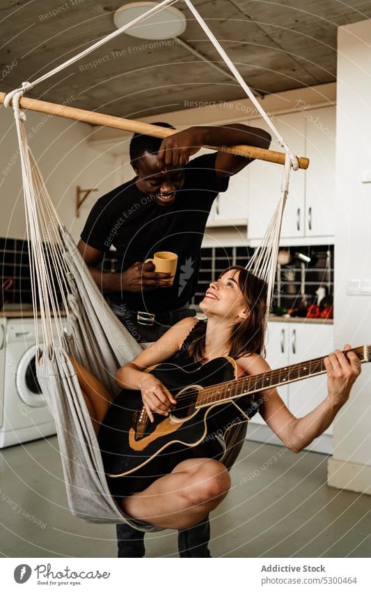 Fröhliche Frau spielt Gitarre mit ihrem Freund Paar spielen Musiker Wochenende Gitarrenspieler Lächeln positiv trinken akustisch Instrument Zusammensein Melodie