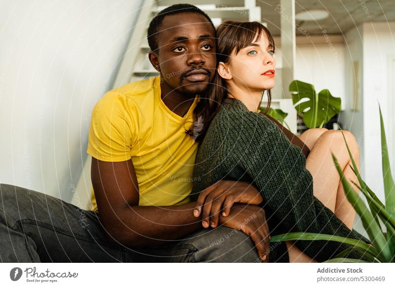 Nachdenkliches Paar, das sich auf einer Treppe umarmt Partnerschaft Liebe Umarmen Umarmung Treppenhaus Zusammensein jung multiethnisch vielfältig