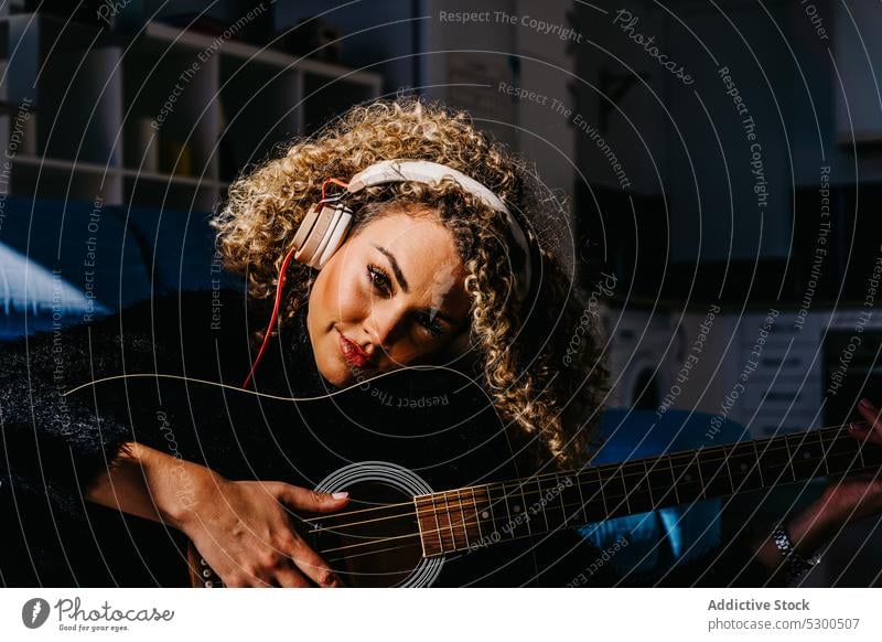 Glückliche Frau spielt Gitarre auf dem Boden spielen Musik Kopfhörer zuhören Lächeln Musiker heiter Instrument Gitarrenspieler üben Hobby akustisch jung Melodie