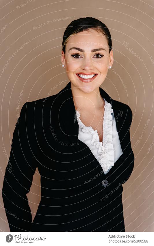 Fleißige Geschäftsfrau in formellem Anzug, stehend vor einem Stoffhintergrund Frau Manager sorgsam Zahnfarbenes Lächeln Studioaufnahme respektabel