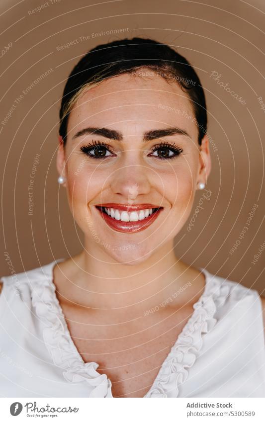 Fröhliche Frau lächelt und schaut in die Kamera vor braunem Hintergrund Model Porträt Zahnfarbenes Lächeln Menschliches Gesicht Charme traumhaft Kosmetik