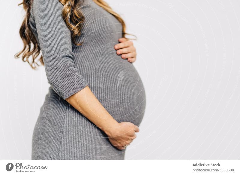 Anonyme schwangere Frau, die ihren Bauch berührt Bauch anfassen glühen warten führen Baby erwarten aufgeregt jung Stil Kleid pränatal Schwangerschaft Babybauch
