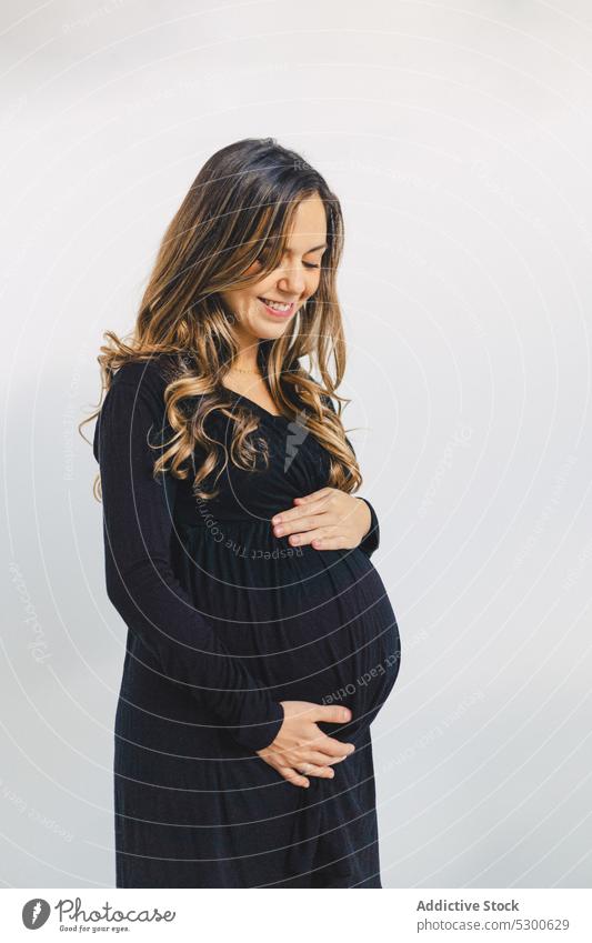 Ruhige schwangere Frau, die ihren Babybauch berührt Glück Liebe Streicheln Bauch anfassen Lächeln warten führen pränatal erwarten jung Unterleib feminin