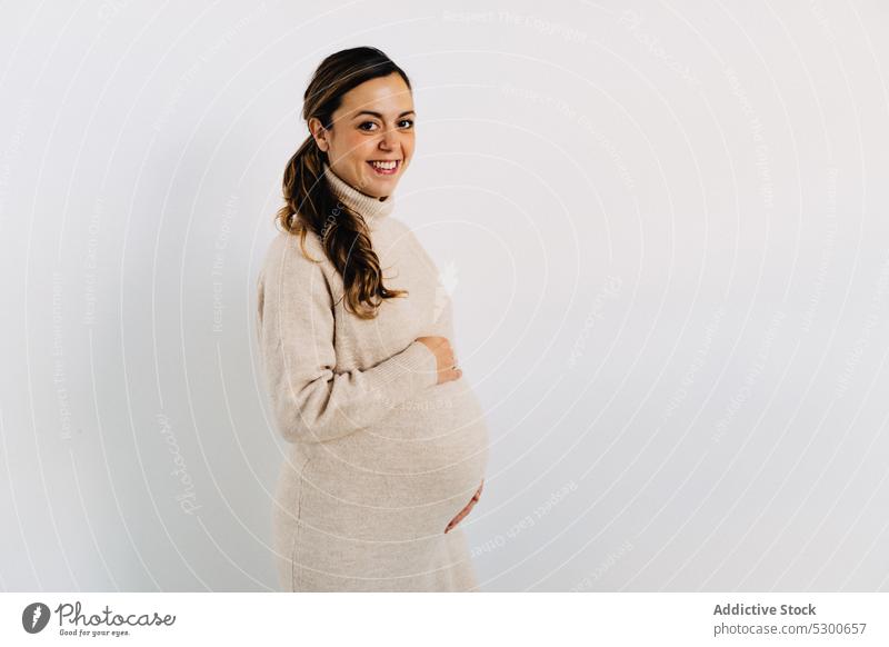 Ruhige schwangere Frau, die ihren Bauch zu Hause berührt Mutterschaftsurlaub Pflege Liebe Bauch anfassen Schwangerschaft Babybauch Windstille jung lange Haare
