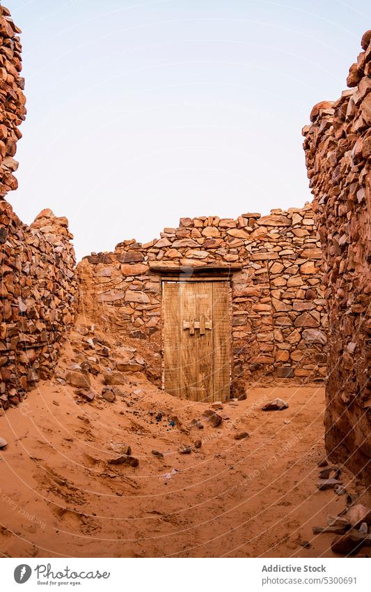Alte verwitterte Holztür in Steinmauer schäbig Verlassen alt Tür Schaden Gebäude Steinwand felsig gealtert vernichten hölzern Sahara Mauretanien Afrika