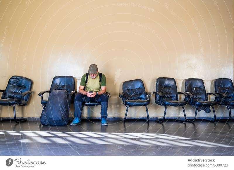 Mann benutzt Mobiltelefon im Wartezimmer eines Flughafens Smartphone benutzend Reisender warten reisen Tourist Passagier Ausflug ruhen männlich lässig Browsen