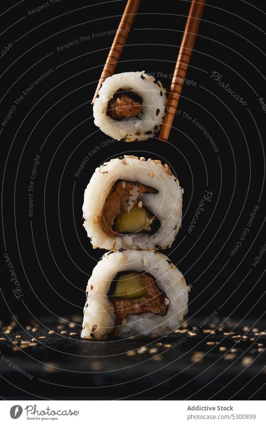 Leckere Sushi-Rollen mit Stäbchen rollen Sesam Asiatische Küche Essstäbchen Lebensmittel Meeresfrüchte appetitlich Mahlzeit Tradition Stapel geschmackvoll