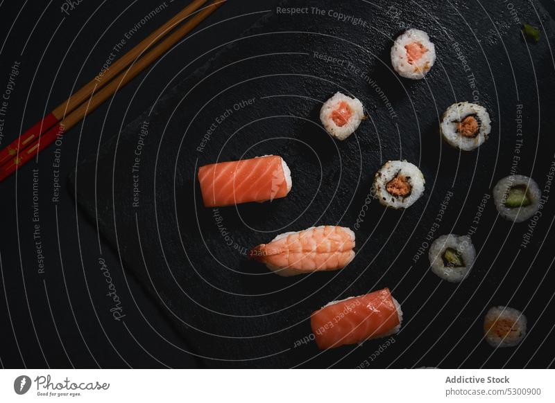 Leckere Sushi-Rollen mit Stäbchen an Bord rollen Japanisch Holzplatte Wasabi Meeresfrüchte Fisch Küche Ingwer Essstäbchen Lebensmittel Asiatische Küche Mahlzeit