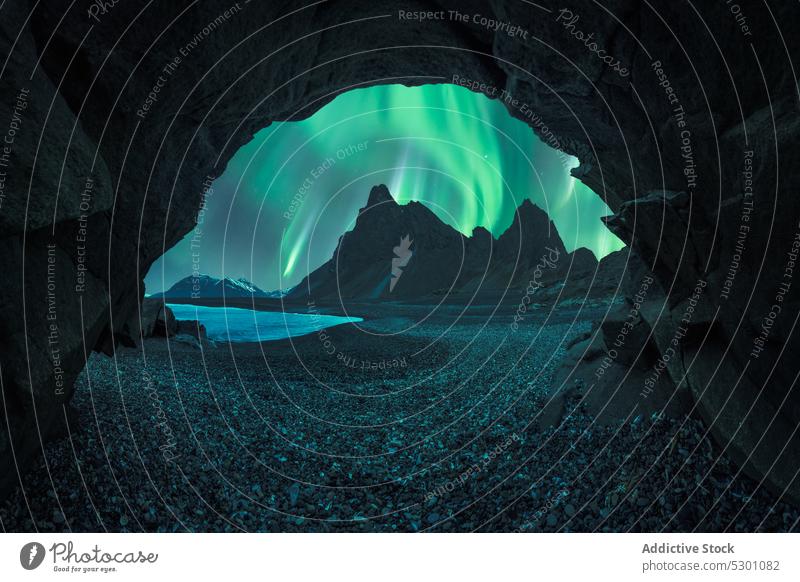 Malerischer Blick auf den schwarzen Sandstrand unter dem Himmel mit Polarlicht Höhle Berge u. Gebirge Nordlicht Wasser Bevorratung Aurora Island Ufer Natur
