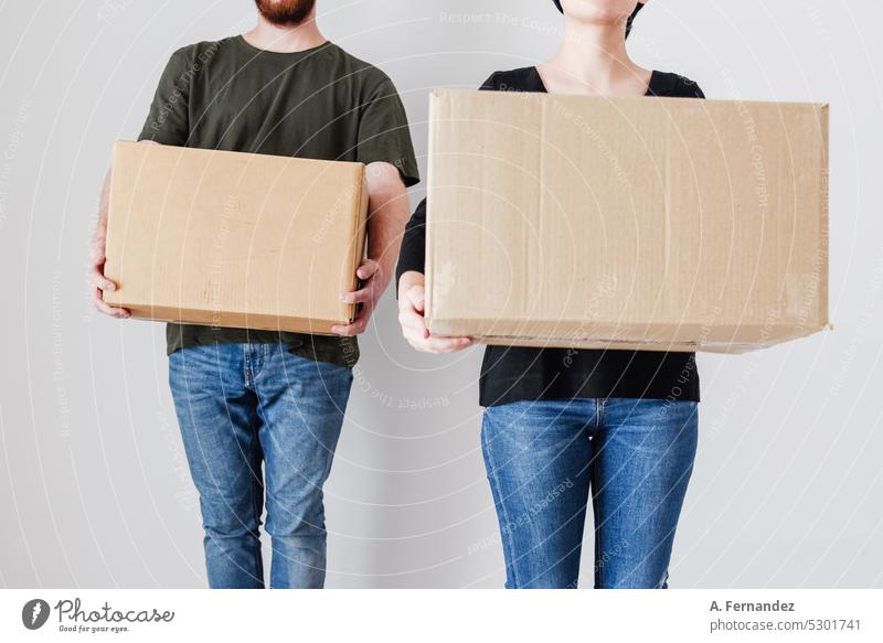 Eine junge Frau und ein Mann halten Pappkartons in einem leeren Raum. Das Konzept, sich zu emanzipieren und ein Haus zu kaufen, um als Paar zu leben. Karton