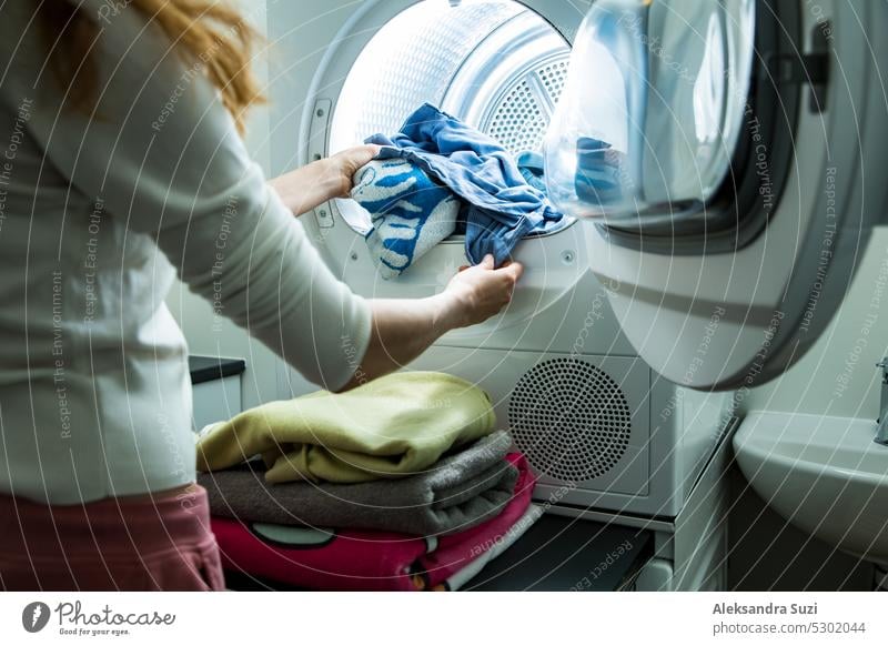 Frau wäscht Wäsche. Trockner Maschine in einem Landry Zimmer zu Hause Trocknen von Kleidung. Hausfrau entlädt Trockner und faltet saubere und trockene Wäsche. Haushalt Hausarbeit Konzept