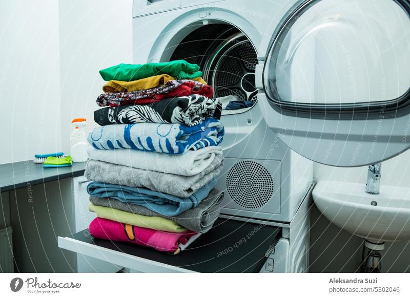 Wäschetrockner in einem Landry-Raum zu Hause, der die Wäsche trocknet. Großer Stapel von sauberer, trockener und gefalteter Kleidung. Konzept der Hausarbeit