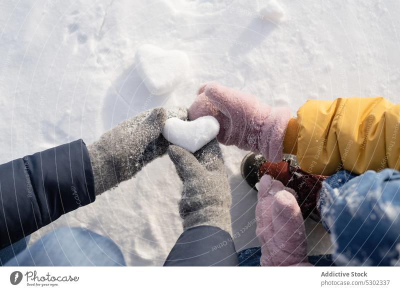 Unbekannte Kinder mit herzförmigem Schneeball Herz Winter Hand spielen Liebe Natur gefroren kalt Symbol romantisch Menschen Umwelt Form Winterzeit Boden
