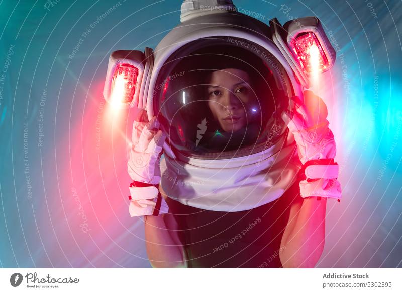 Frau im Kosmonautenhelm mit Neonlicht Astronaut Schutzhelm Model ernst selbstbewusst neonfarbig futuristisch Porträt Vorschein Stil leuchten glühen Licht