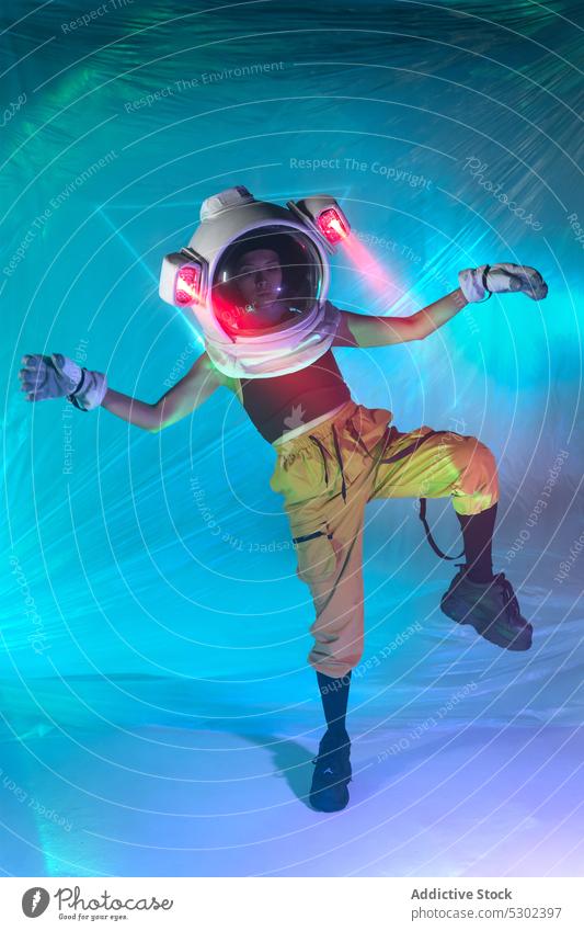 Frau mit Astronautenhelm tanzt auf dem Boden Tanzen neonfarbig Schutzhelm Kosmonaut Stil futuristisch leuchten Energie selbstbewusst Atelier sich[Akk] bewegen