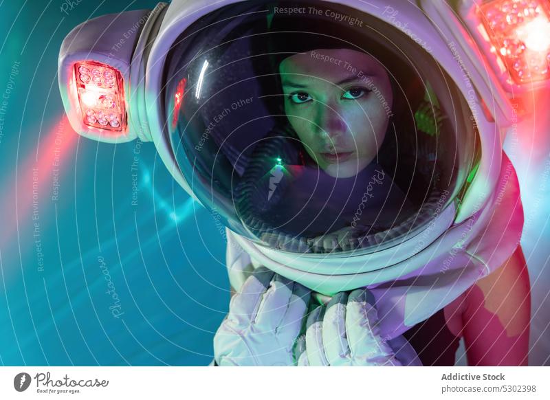 Frau im Kosmonautenhelm mit Neonlicht Astronaut Schutzhelm Model ernst selbstbewusst neonfarbig futuristisch Porträt Vorschein Stil leuchten glühen Licht