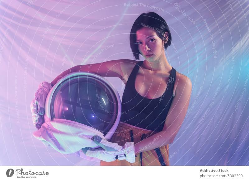 Selbstbewusste Frau mit Helm im Studio selbstbewusst Porträt ernst Schutzhelm Atelier neonfarbig Windstille behüten Astronaut Kosmonaut futuristisch Fokus