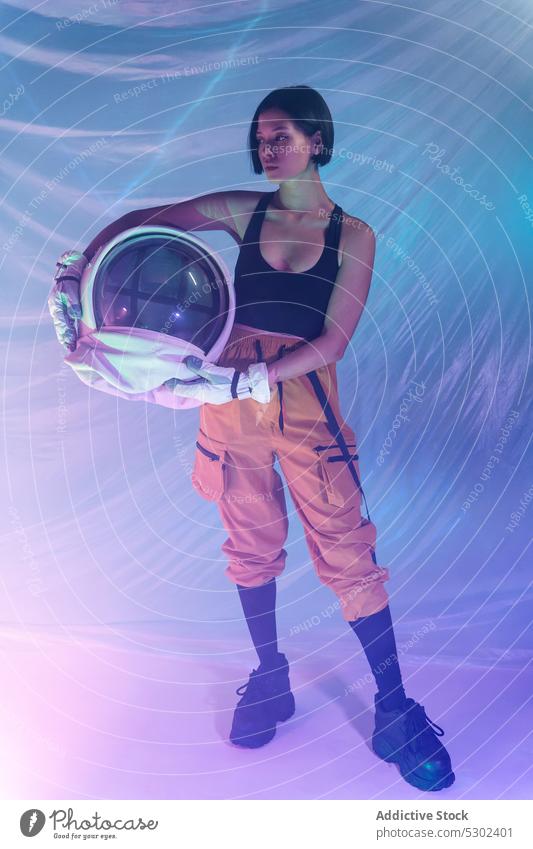 Selbstbewusste Frau mit Helm im Studio selbstbewusst ernst Schutzhelm Atelier neonfarbig Windstille behüten Astronaut Kosmonaut futuristisch Fokus nachdenklich