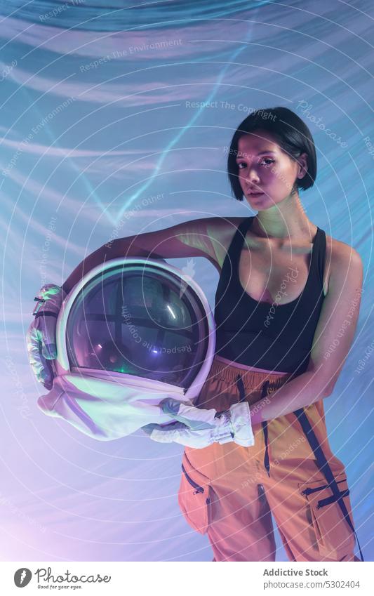 Selbstbewusste Frau mit Helm im Studio selbstbewusst Porträt ernst Schutzhelm Atelier neonfarbig Windstille behüten Astronaut Kosmonaut futuristisch Fokus