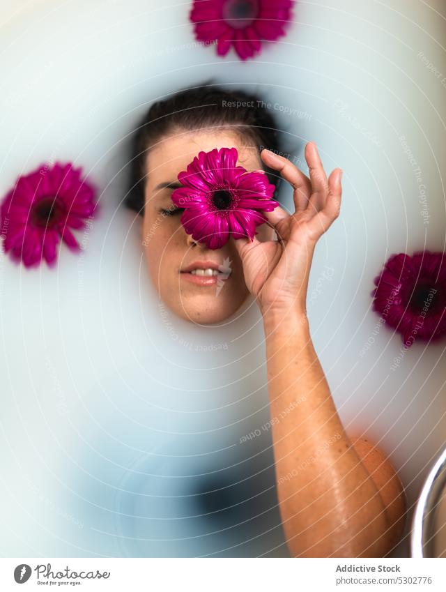 Frau bedeckt Auge mit rosa Blume während des Badens Augen abdecken melken Badewanne Routine friedlich Freizeit Hygiene Spa Wellness ruhen Kälte natürlich