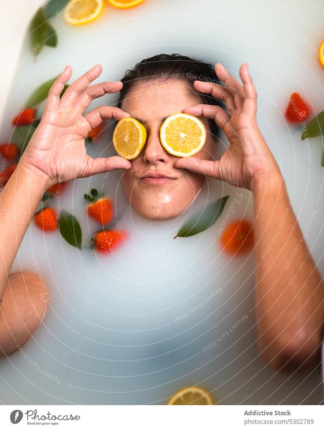 Frau bedeckt Augen mit Orangen in der Badewanne Augen abdecken orange Scheibe melken Erdbeeren Blatt Körperpflege Erholung lustig kreativ Wellness Spa Routine