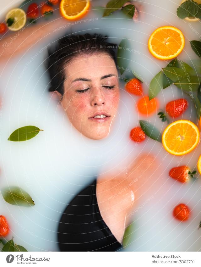Entspannte Frau nimmt ein Bad mit Früchten und Beeren zu Hause orange Scheibe melken Blatt Windstille Erdbeeren Spa Verfahren Freizeit Gesundheit Therapie