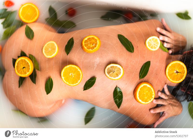 Crop-Frau mit Zitrusscheiben auf dem Rücken Zitrone orange Zitrusfrüchte Scheibe melken Bad Therapie Pflege Leckerbissen Erholung Gesundheit Hautpflege