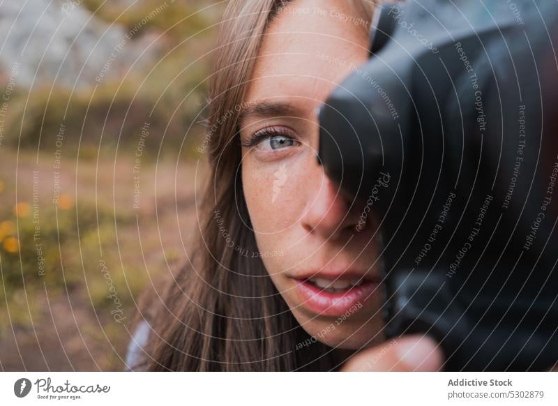 Halbes Gesicht einer jungen Reisefotografin Frau professionell Fotograf Fotoapparat Tierhaut Hobby schießen Linse fotografieren Konzentration einfangen