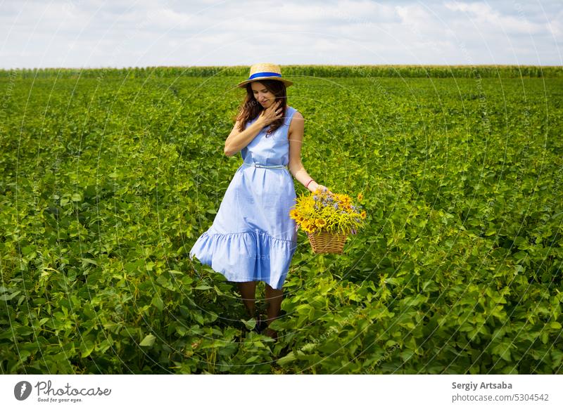 Schönes Mädchen mit Strohhut steht auf einer grünen Wiese mit einem Blumenstrauß Frau Leben Gesundheit Sommer Natur Kleid Glück Frühling Schönheit Feld Aktion