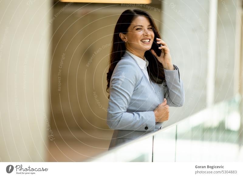 Junge Geschäftsfrau, die im Büroflur ein Mobiltelefon benutzt Frau Kaukasier professionell Business Flur Menschen Telefon Person selbstbewusst sprechend