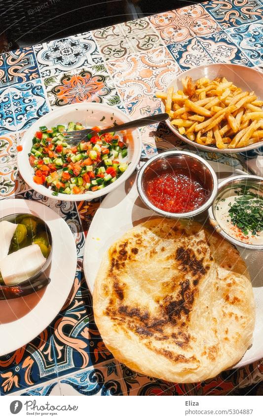 Verschiedene Gerichte auf einem Tisch im Restaurant Pommes Stadt Essen Salat Malawach Malawah Lebensmittel Foodfotografie Tischdecke bunt Ernährung