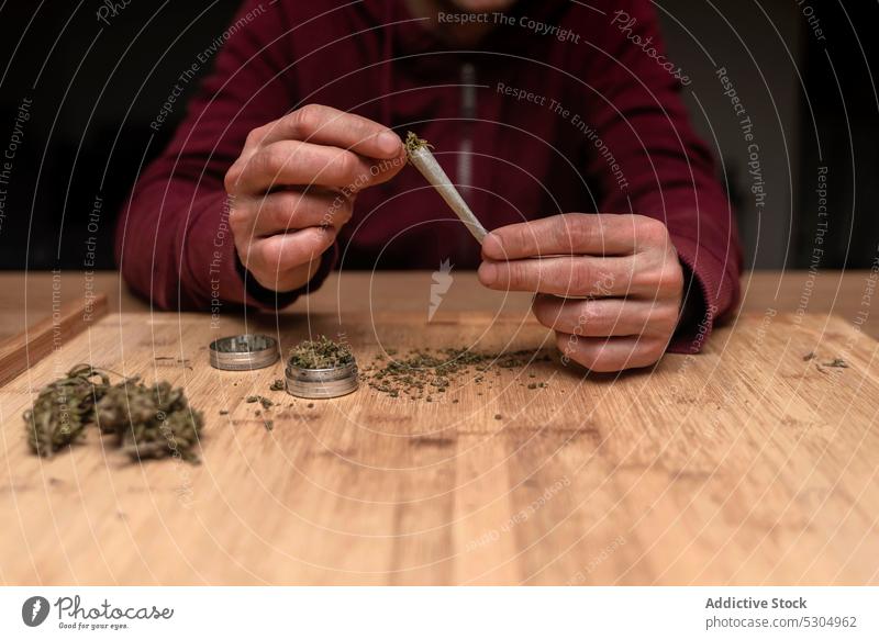 Unbekannter Mann füllt Joint mit Cannabis Marihuana Unkraut stumpf gerollt Rauch Gelenk Schleifmaschine ganja Medikament ungesetzlich Cannabinoid natürlich