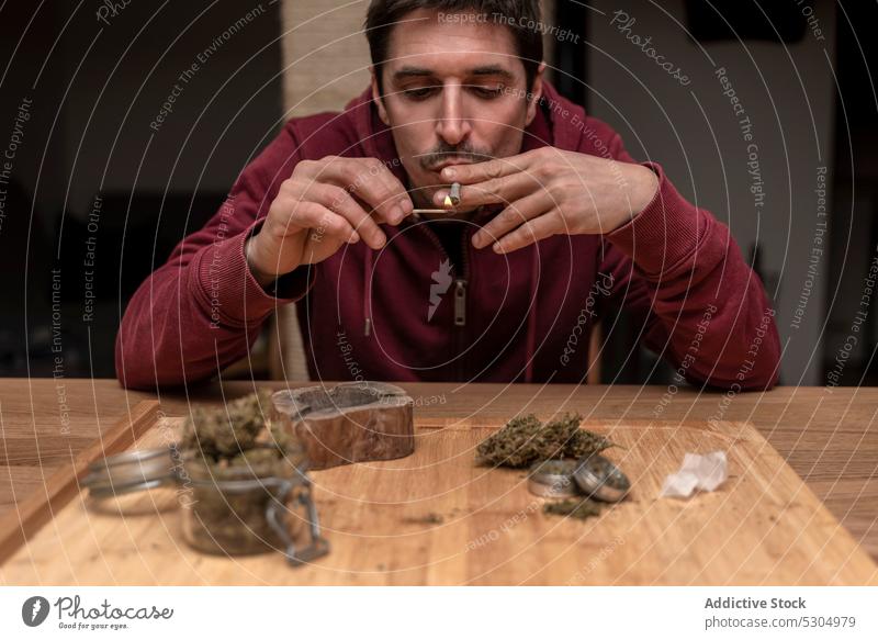 Erwachsener Mann raucht Cannabis zu Hause Rauch Raucherin Marihuana Licht Gelenk stumpf Streichholz ganja Habitus männlich medizinisch legalisieren Nikotin