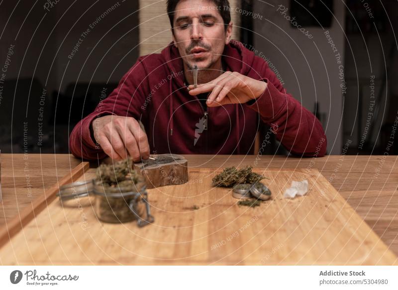 Erwachsener Mann raucht Cannabis zu Hause Rauch Raucherin Marihuana Licht Gelenk stumpf Streichholz ganja Habitus männlich medizinisch legalisieren Nikotin