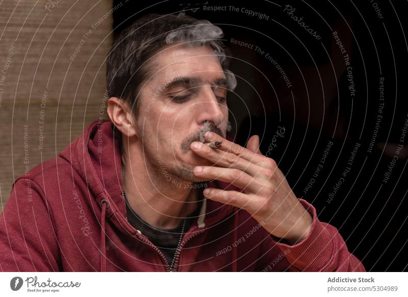 Erwachsener Mann mit Schnurrbart raucht Marihuana Blunt Rauch Raucherin inhalieren medizinisch stumpf Gelenk Licht Medikament Cannabis männlich Betäubungsmittel