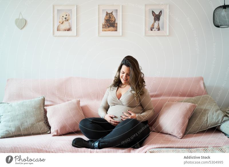 Positive schwangere Frau entspannt sich auf dem Sofa Bauch mütterlich erwarten berühren Glück Schwangerschaft Lächeln Komfort heimwärts vorwegnehmen Liege