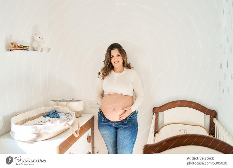 Glückliche Frau, die ihren Bauch berührt schwanger erwarten mütterlich sich[Akk] entspannen Kinderzimmer Schwangerschaft Kinderkriegen pränatal Mutterschaft