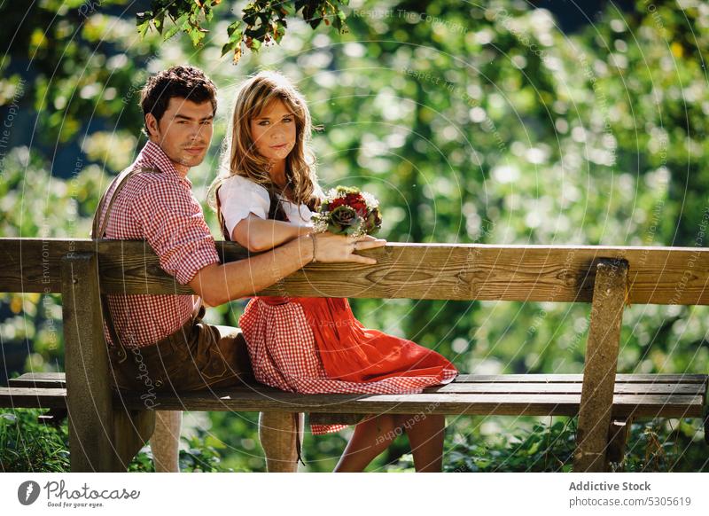 Ehepaar in traditioneller Kleidung auf einer Bank Paar Sitzen Garten Österreicher Bekleidung Lächeln sonnig tagsüber Mann Frau Park Glück Lifestyle Freizeit